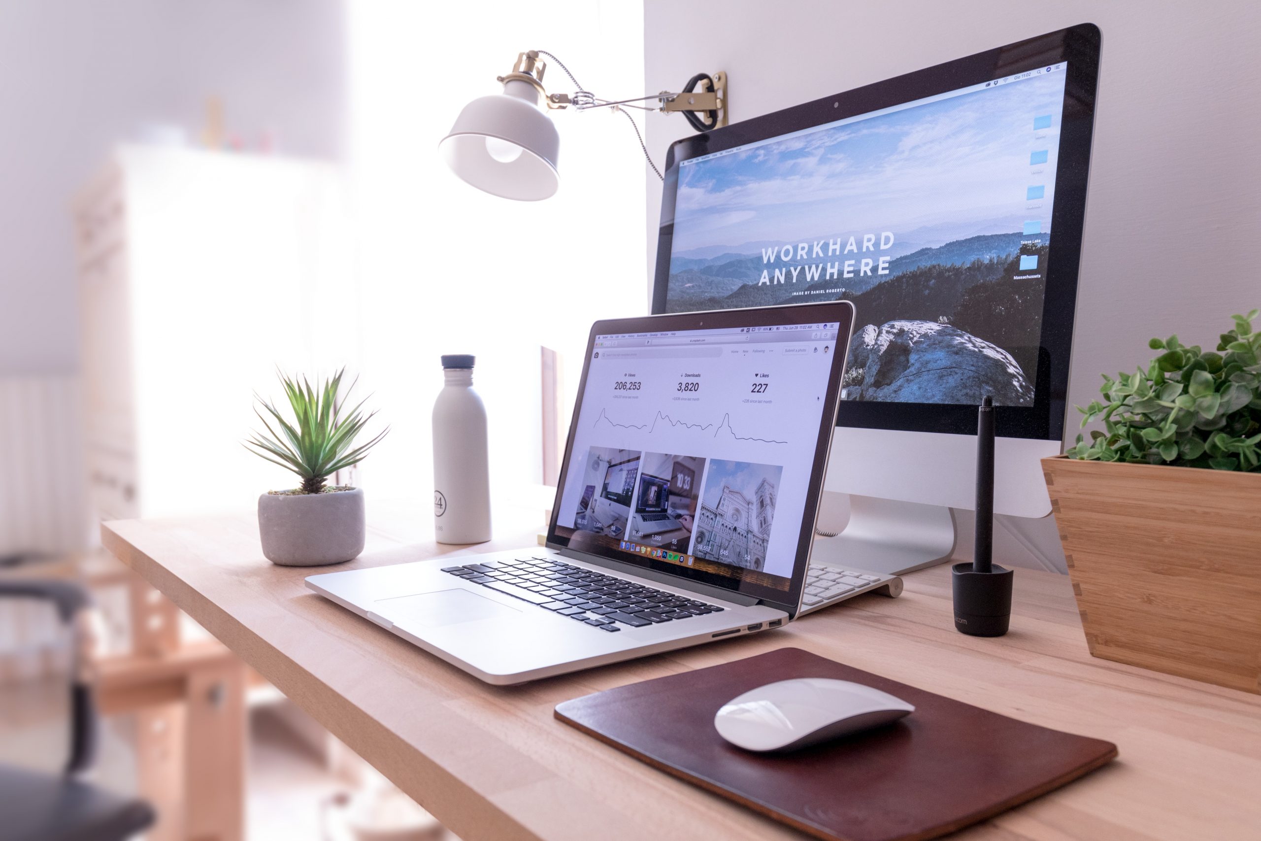 a laptop and larger desktop behind it