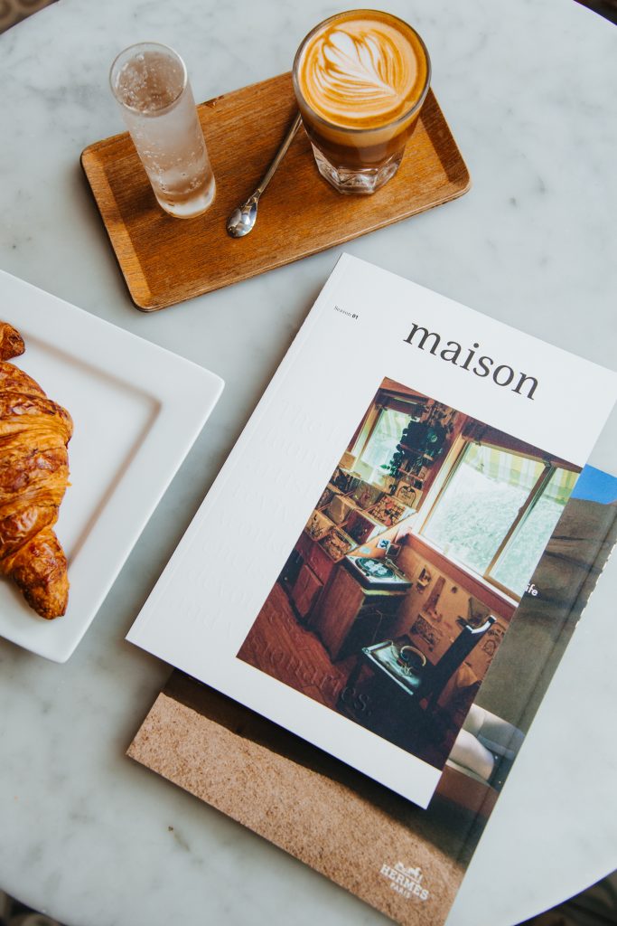 table set with an espresso, magazine and a croissant
