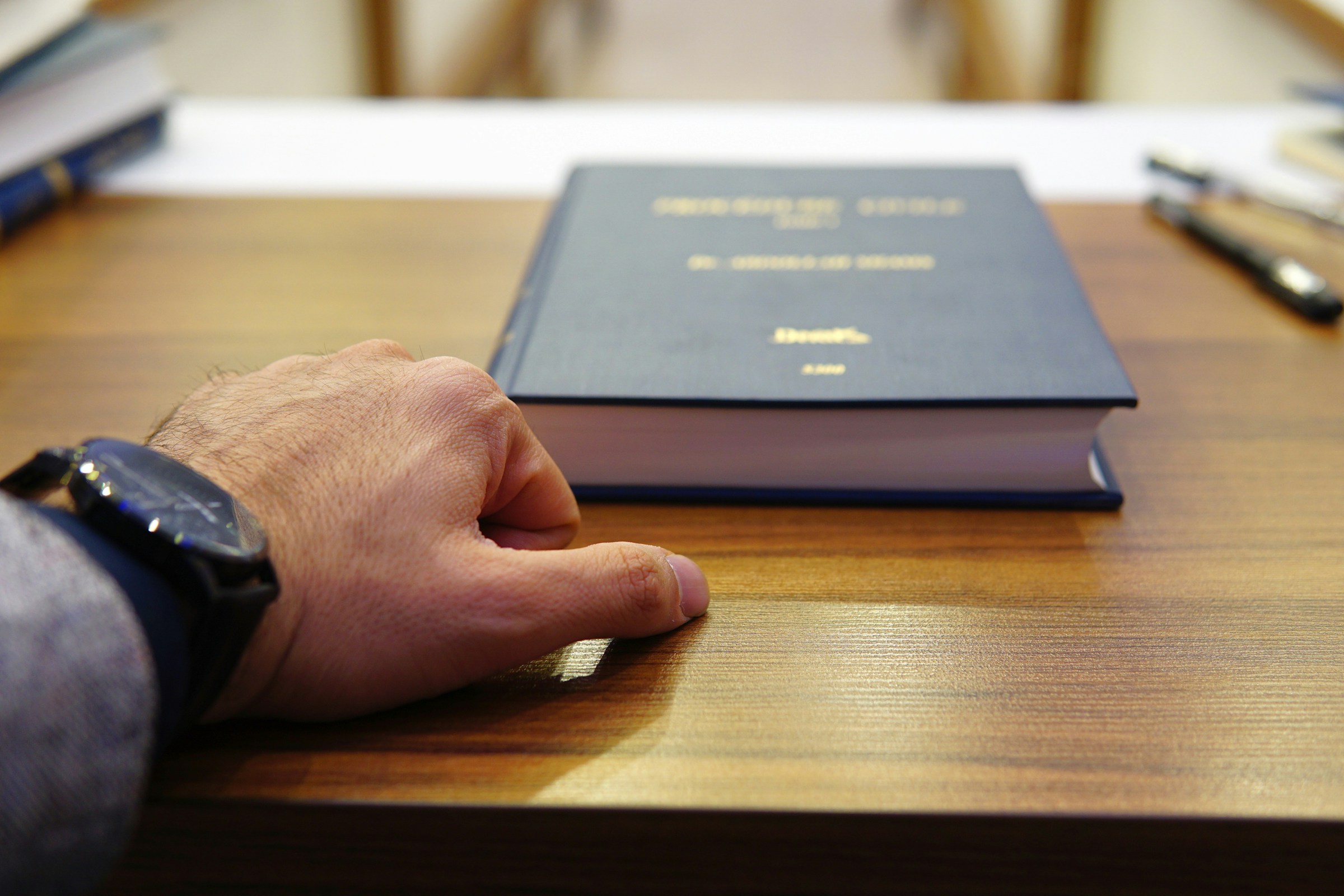 The hand of a man on a desk with a legal book.