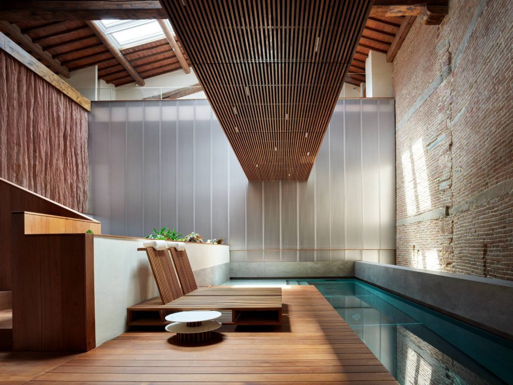 An indoor swimming pool appointed by luxurious wood decking.