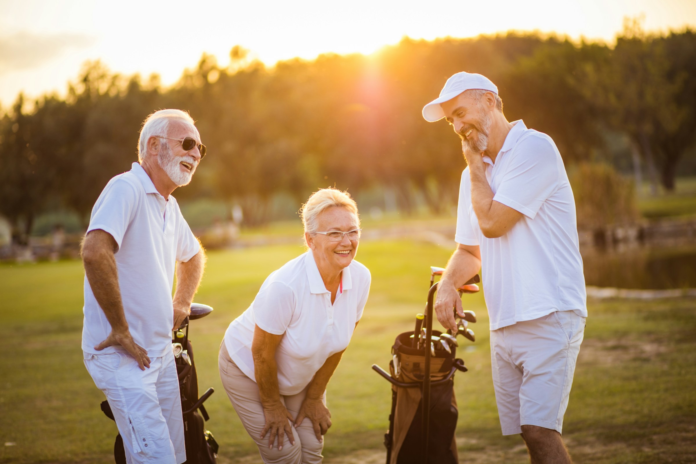 older couple playing golf with a caddy or golf coach